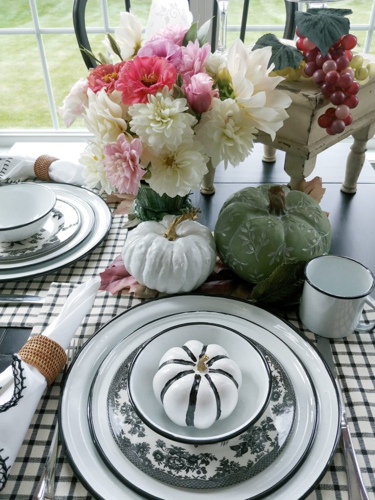 A table topped with plates and a faux pumpkin