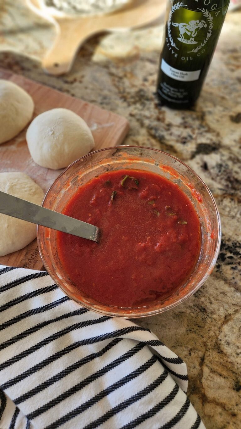 pizza sauce in glass bowl with pizza dough on side