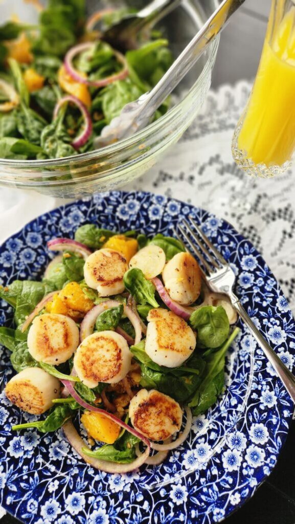 scallop salad on dish with glass of orange juice on side