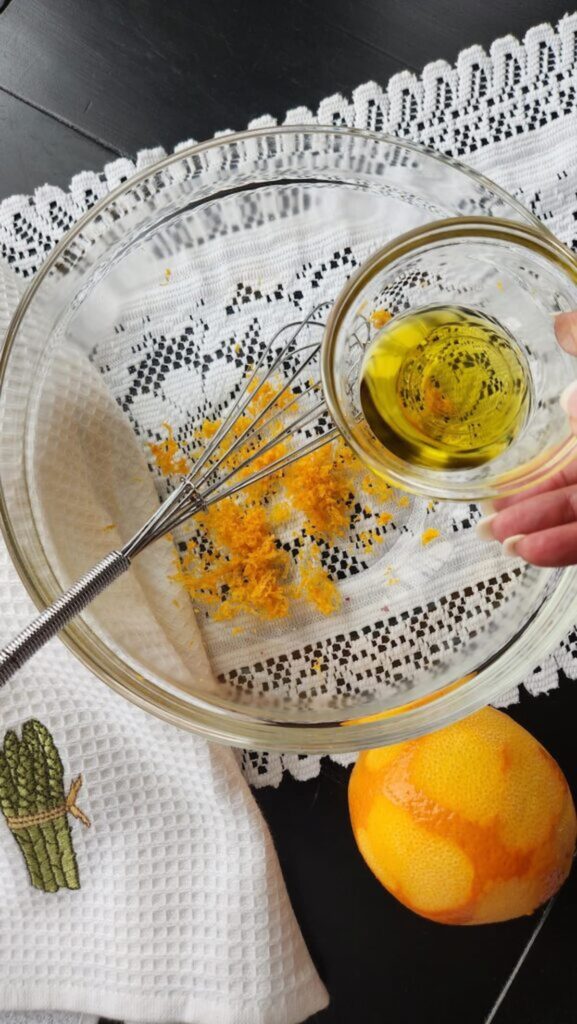 adding olive oil to zested orange in bowl