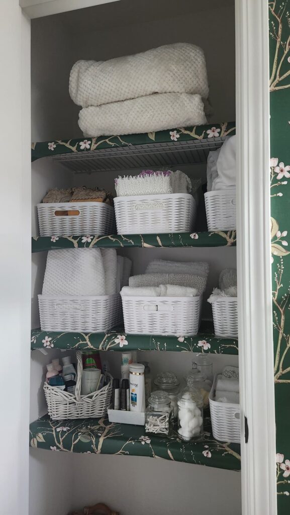 linen closet with wallpapered shelves