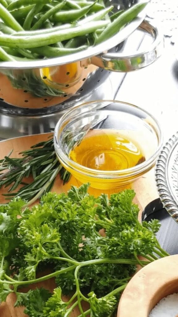 olive oil in small glass bowl with herbs on the side