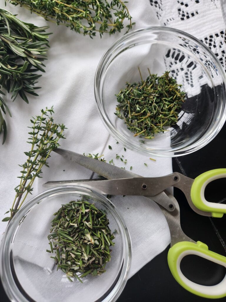 overhead of herbs being chopped with herb scissors